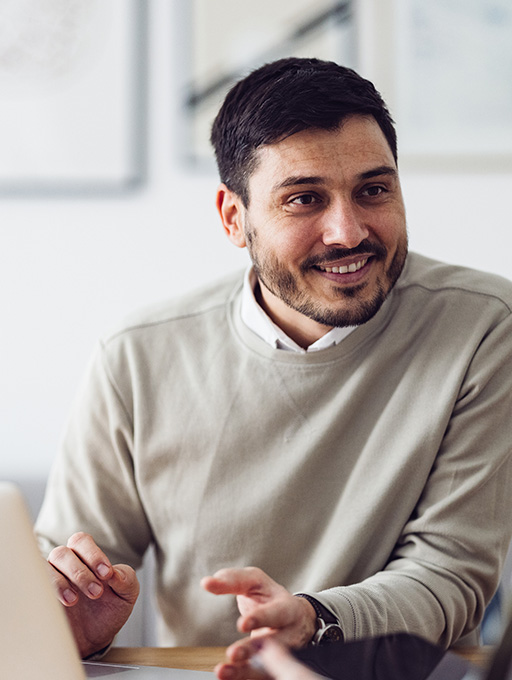 Smiling man with taupe sweater and white collared shirt