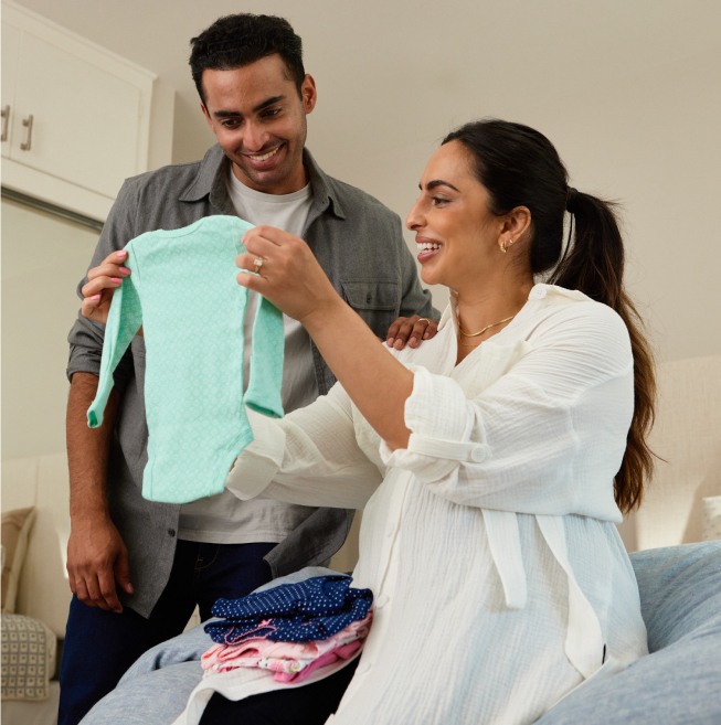 Couple looking at new born pajamas together smiling